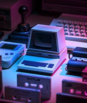 Small vintage CBM computer with built-in screen and audio cassettes in the foreground