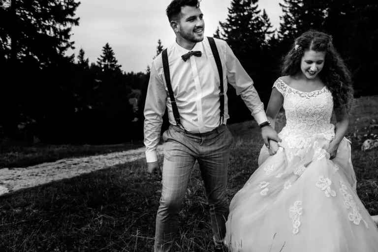 Couple en tenue de cérémonie marchant main dans la main dans l'herbe
