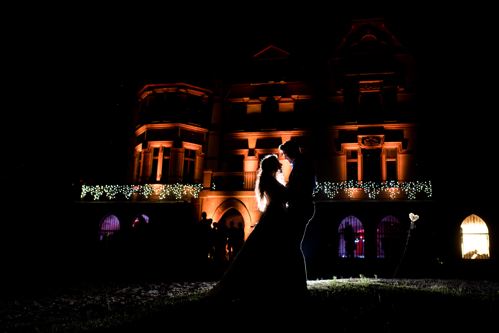 Photo de nuit des mariés devant la demeure