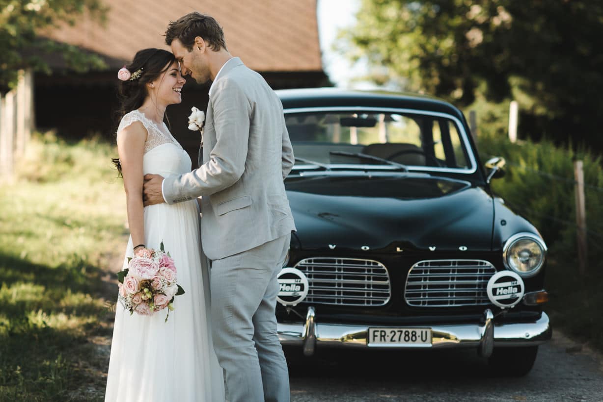 Les mariés s'embrassent devant la magnifique Volvo