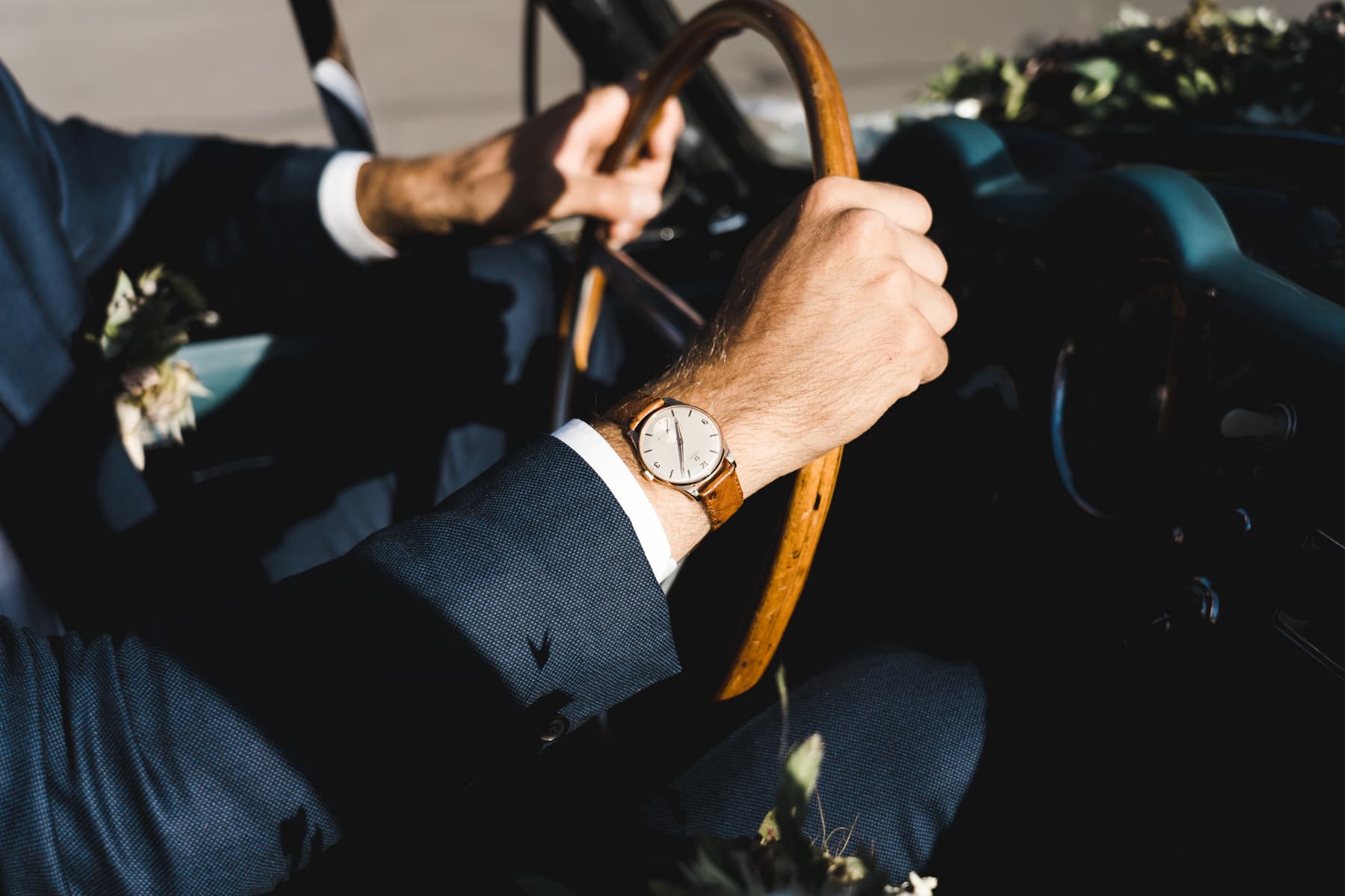 Le mariée conduit une oldtimer avec une belle montre à son poignet