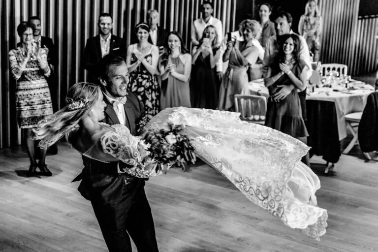 Couple en noir et blanc tournoyant sur une piste de danse entouré d'invités
