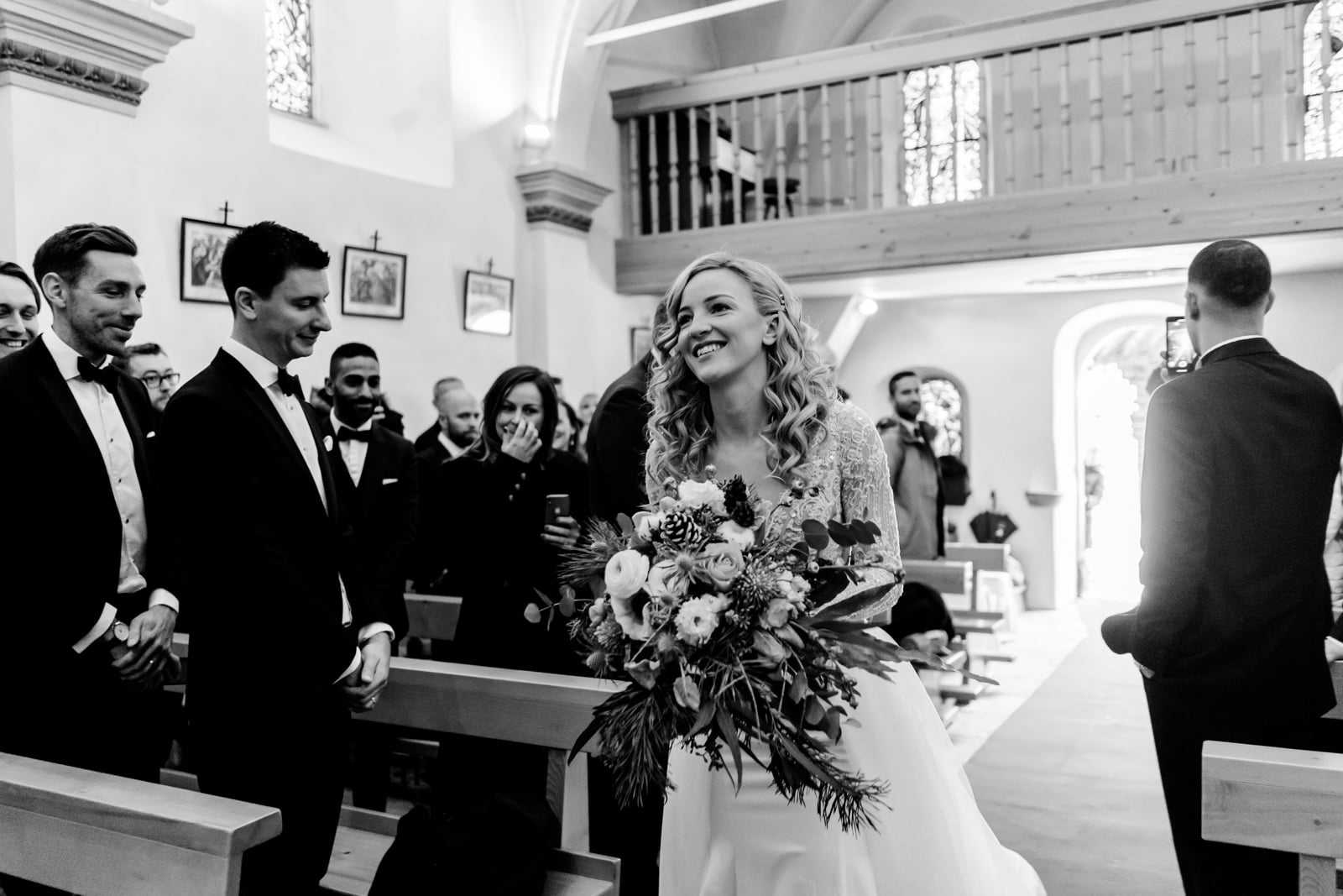 La mariée entre dans la chapelle de Verbier en fixant son futur mari
