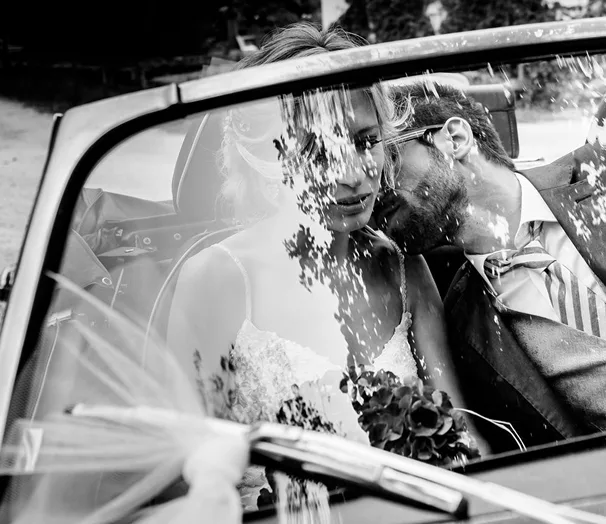 Couple en noir et blanc reflété dans le pare-brise d’une voiture ancienne