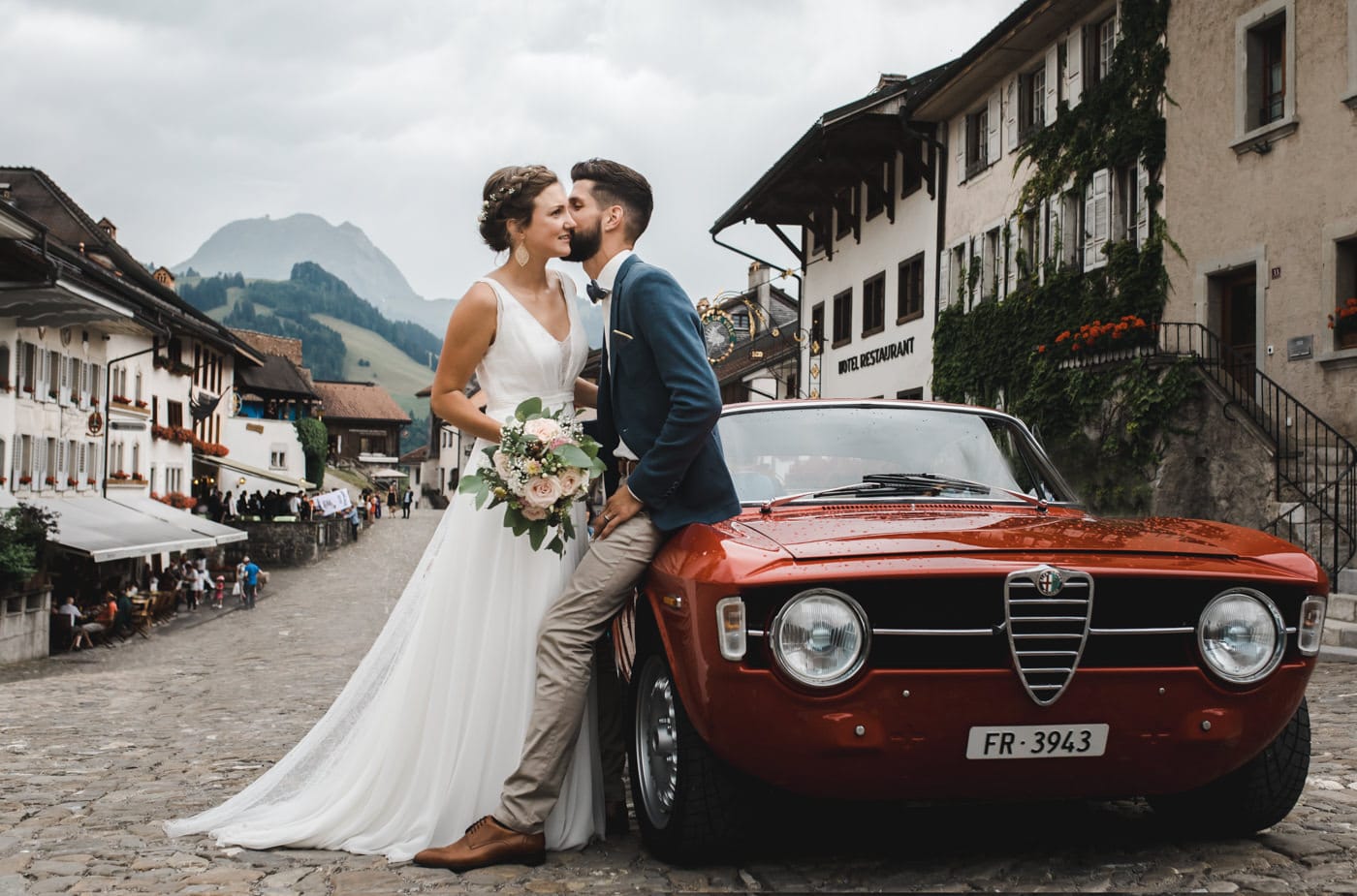 Les mariés s'échangent un bisou devant l'oldtimer