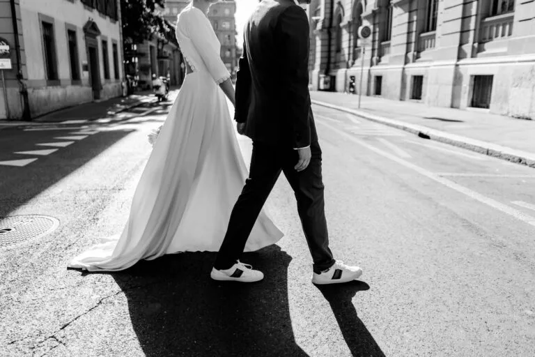 Couple en tenue de cérémonie marchant main dans la main dans une rue