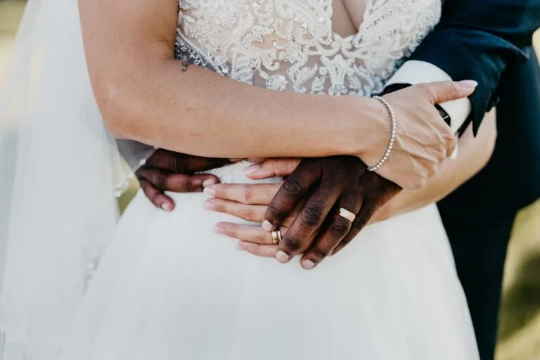 Deux mains entrelacées sur la taille d'une robe de mariée en dentelle