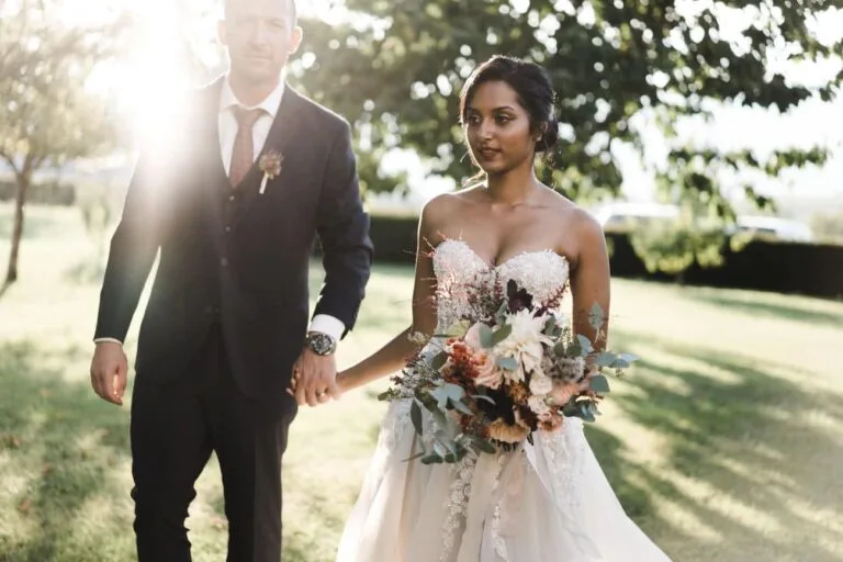 Couple main dans la main, la mariée tenant un bouquet, lumière solaire