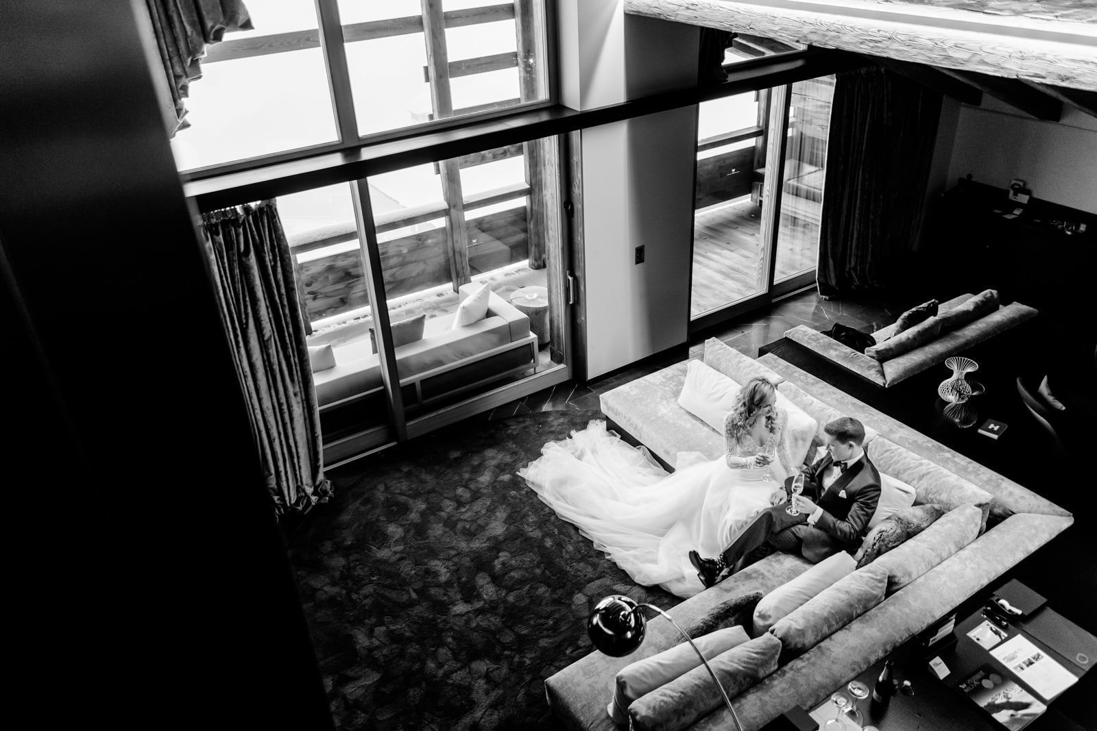 Le couple boit un verre de champagne à l'écart de la foule dans leur suite de l'hotel W de Verbier