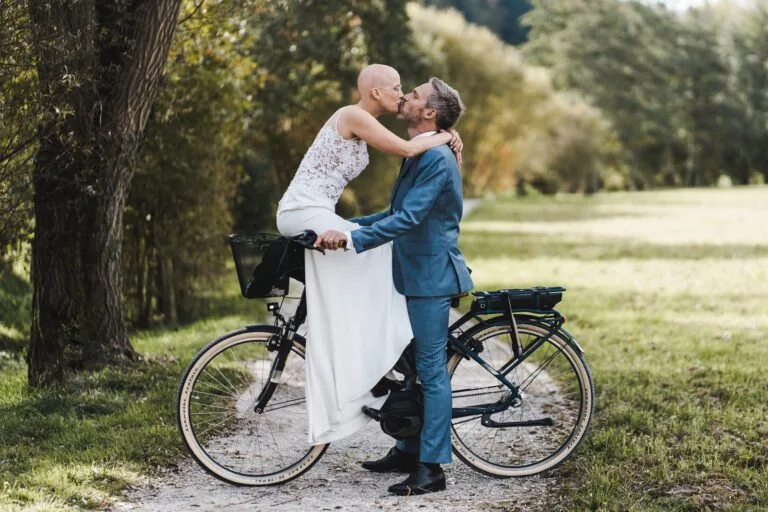 Couple s'embrassant tendrement sur un vélo dans un parc arboré
