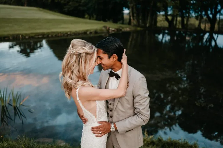 Couple en tenue de cérémonie face à face devant un étang calme