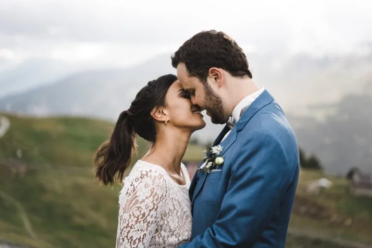 Couple s'embrassant doucement le nez face à un paysage montagneux flou