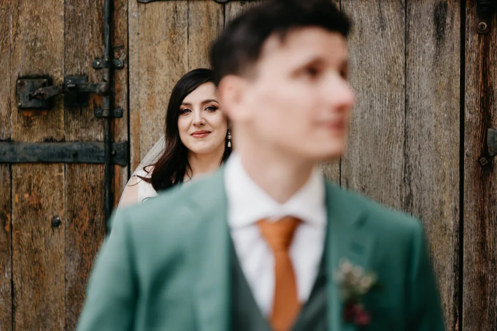 Femme au regard doux devant une porte en bois massif et ferrures