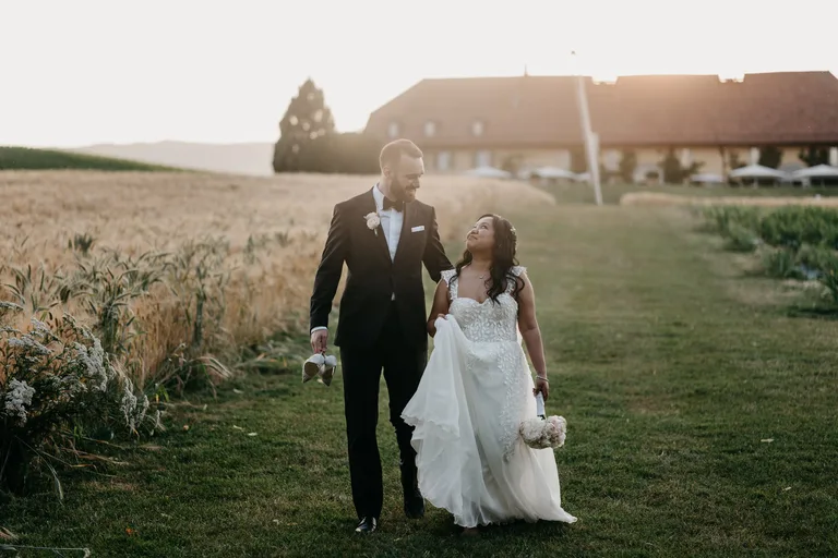 Couple en tenue de cérémonie marchant main dans la main dans l'herbe